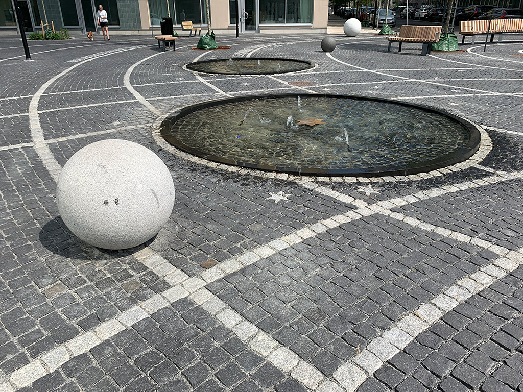 Fontäner, markläggning av mörk gatsten och vitt klot.