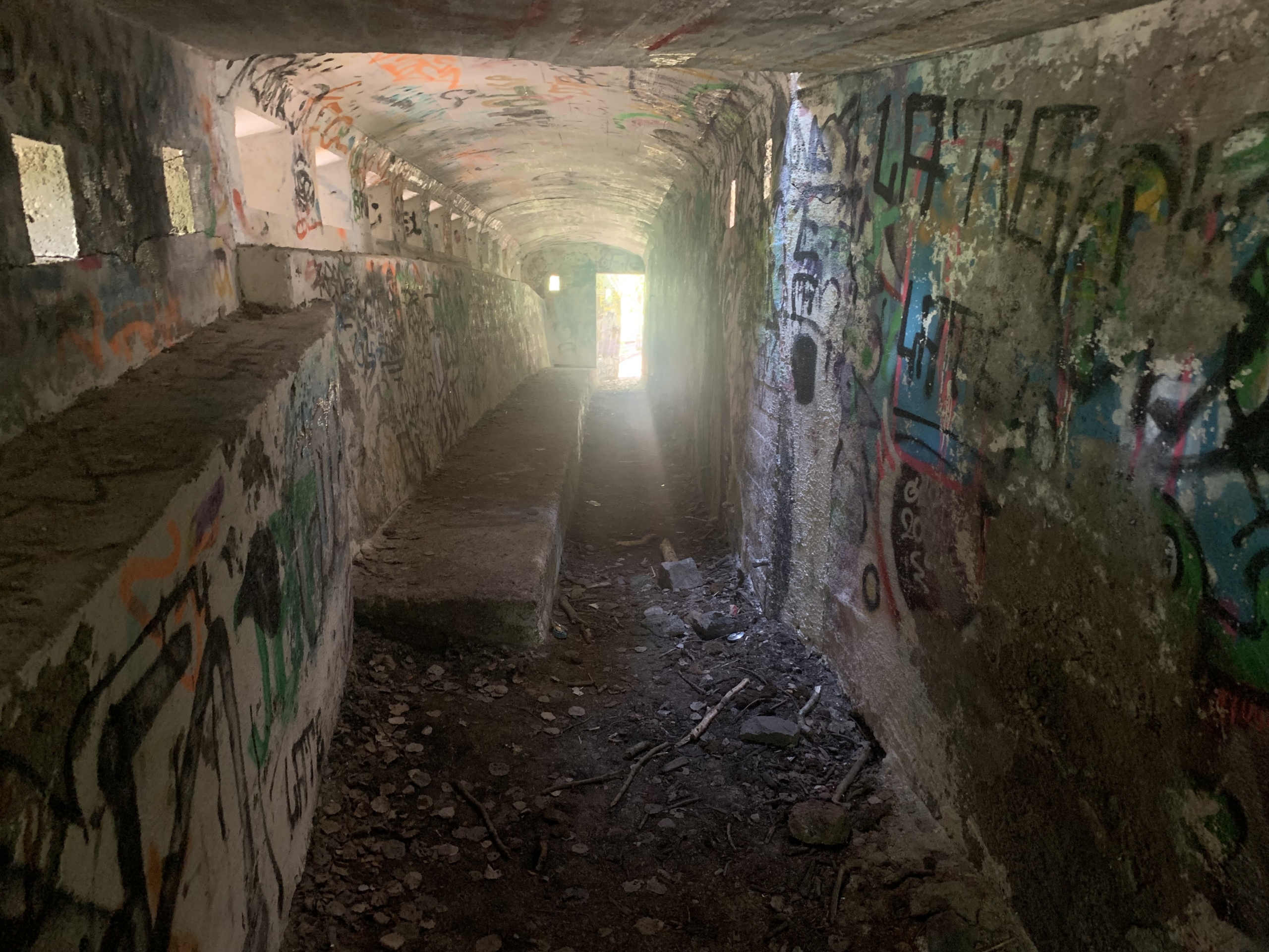 Interiörbild av en övergiven försvarsanläggning. En låg korridor som är full med klotter.