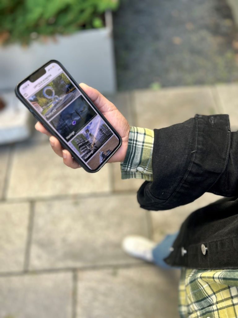 En person håller i en mobiltelefon och navigerar i appen Upptäck konsten.